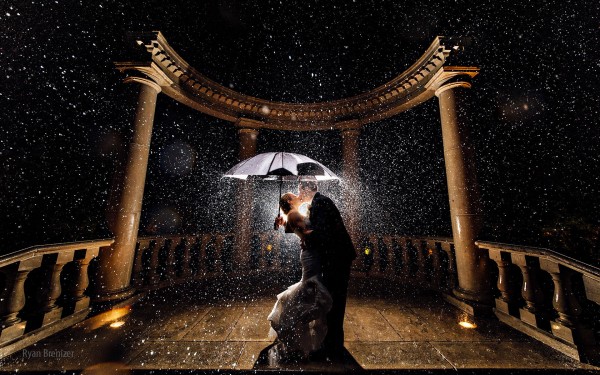 Newly Married couple kissing in rain