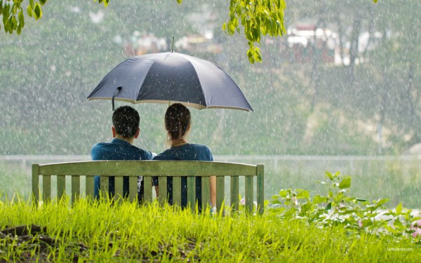 Romantic couple sitting in park while raining
