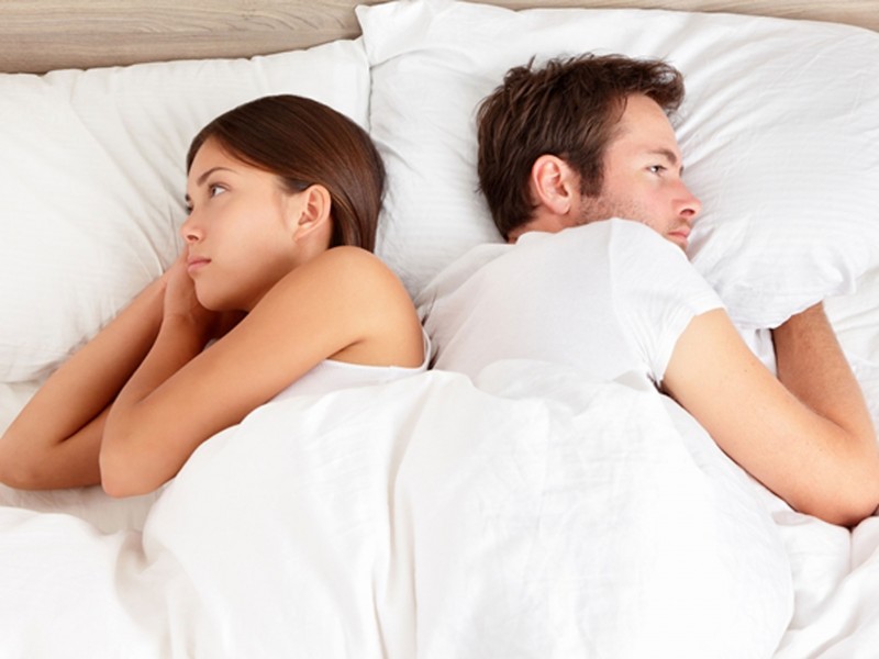 Unhappy couple sleeping in bed turning around their face