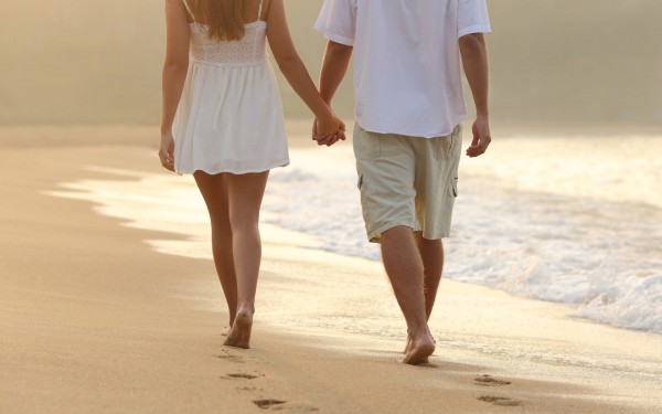 cute couple holding hand walking in seashore